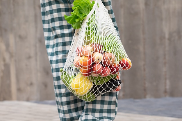 Femme marchant et achetant des fruits et légumes avec un sac de produits Eco en coton réutilisable. Concept de mode de vie zéro déchet