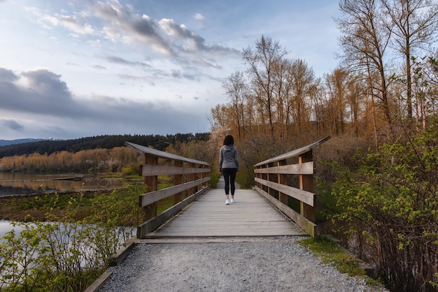 Femme marchant sur un chemin en bois avec des arbres verts dans Shoreline Trail