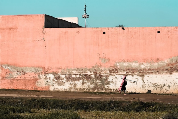 Une femme marchant contre le mur et le ciel en ville.