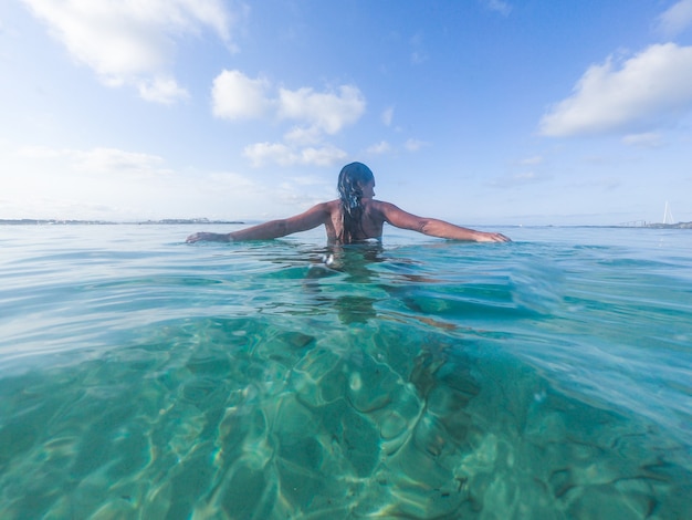 Femme marchant dans la mer, le dos tourné. Île de Formentera, Espagne. Vue au niveau de l'eau, caméra immergée à 50%, photo avec dôme sous-marin.