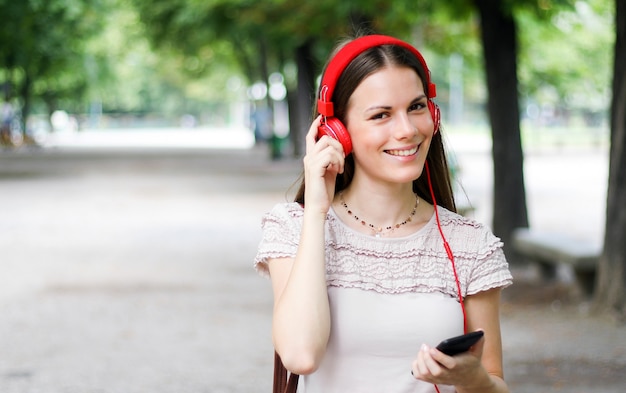 Femme marchant dans un parc tout en utilisant son smartphone pour écouter de la musique