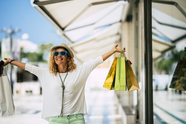 Photo une femme marchant dans la rue de la ville avec quelques magasins - faire du shopping avec beaucoup de sac sur les mains - mode de vie des acheteurs