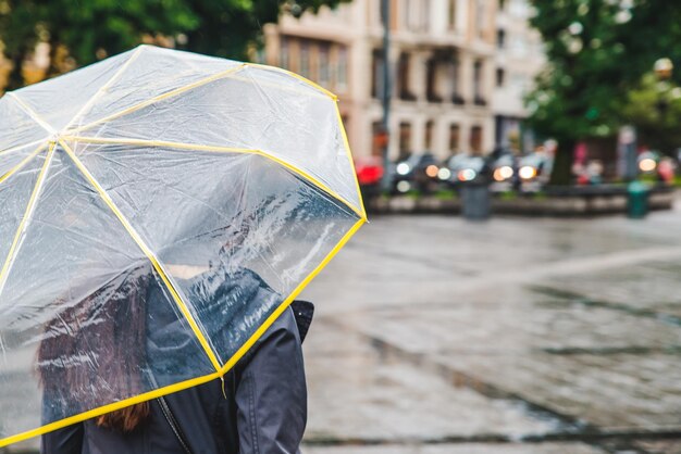 Femme marchant dans des rues pluvieuses humides sous un espace de copie de parapluie transparent