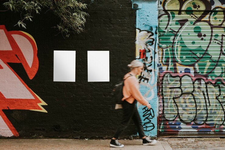 Photo femme marchant devant une peinture murale d'art de rue et des affiches vierges