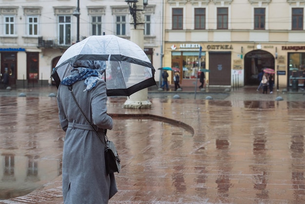 Femme marchant avec un parapluie transparent sous la pluie dans l'espace de copie de la rue de la ville