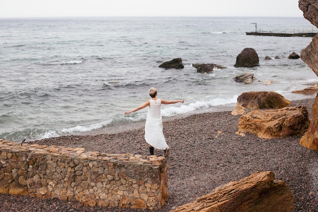 Femme marchant près de la mer Modèle féminin aux cheveux courts ayant une promenade par temps nuageux Nature concept de temps libre