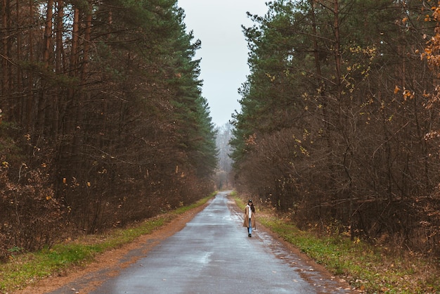 Femme marchant sur une route d'automne vide