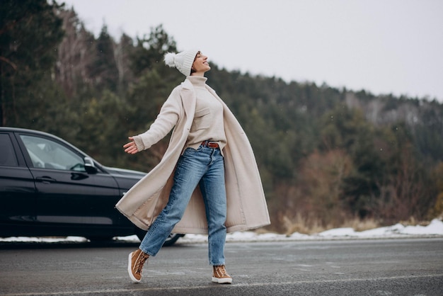 Femme marchant traverser la route par sa voiture dans la forêt d'hiver