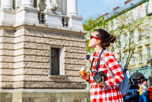 Femme marchant en ville avec caméra et espace de copie de crème glacée