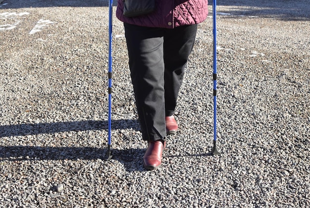 Une femme marche avec des béquilles sur un chemin de gravier.