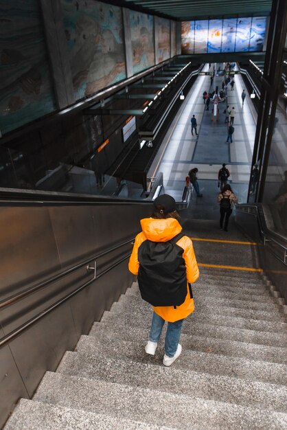 Une femme marche dans les escaliers jusqu'à la station de métro.