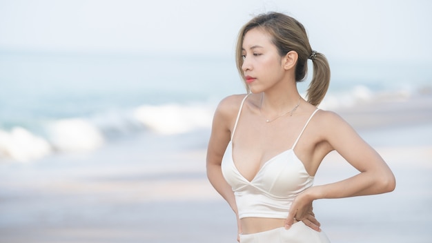 Une femme marche le long de la plage avec la mer.