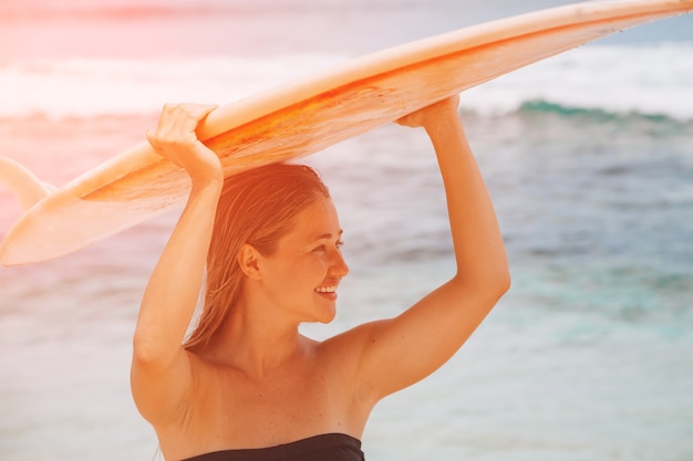 Une femme marche avec une planche de surf dans la mer