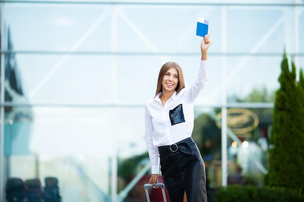 Femme marche près de l'aéroport avec passeport valise et billet passager