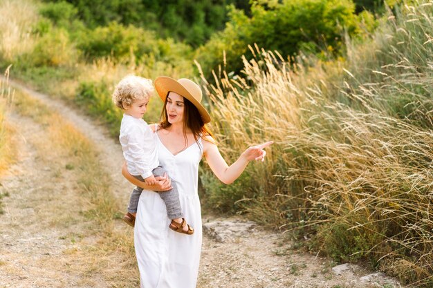 La femme marche avec son fils dans ses bras