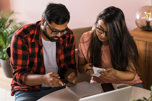 Une femme et un mari sérieux planifient un budget en vérifiant les finances d'une jeune femme à l'aide d'un calculateur en ligne