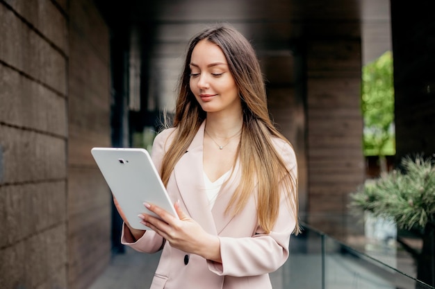 Photo une femme de marketing utilise une tablette en se tenant debout dans le contexte d'un immeuble de bureaux
