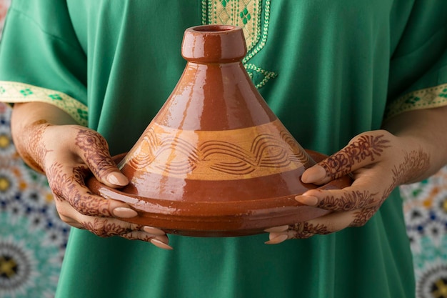 Une femme marocaine avec des mains peintes au henné tenant un tagine