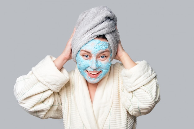 Femme avec masque d'argile facial au salon spa ou à la maison, thème de soins de la peau. Fille enlève le masque cosmétique d'alginate. Masque facial, traitement de beauté spa avec espace copie