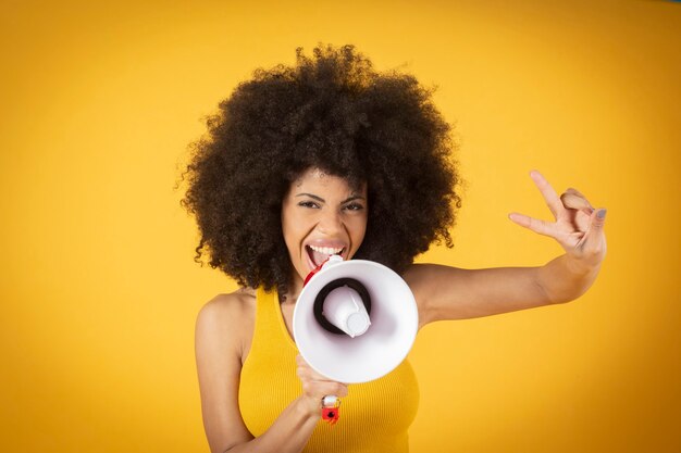 Une femme avec un masque et des cheveux afro tient le drapeau de la fierté gay lgbtq fond jaune