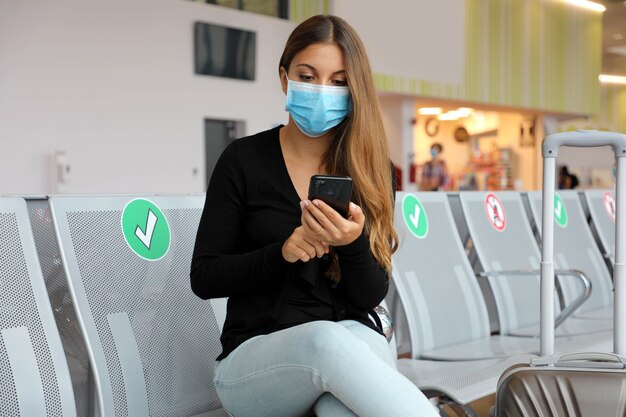 Femme avec masque chirurgical en attente à l'aéroport