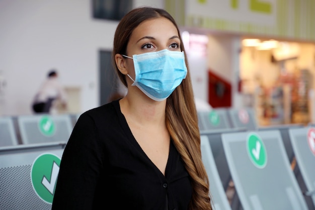 Femme avec masque chirurgical en attente à l'aéroport