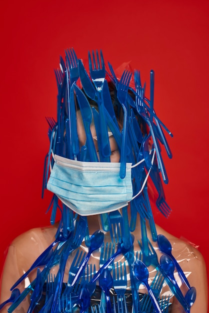 Femme avec masque couvrant son visage et son corps avec de la vaisselle en plastique bleu