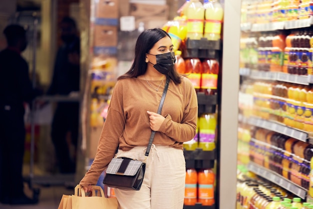 Femme en masque d'épicerie et de sécurité dans les supermarchés contre les virus et la vente au détail Réfrigérateur de choix d'épicerie avec stock et cliente à l'abri des bactéries dans le service commercial et la vente en magasin