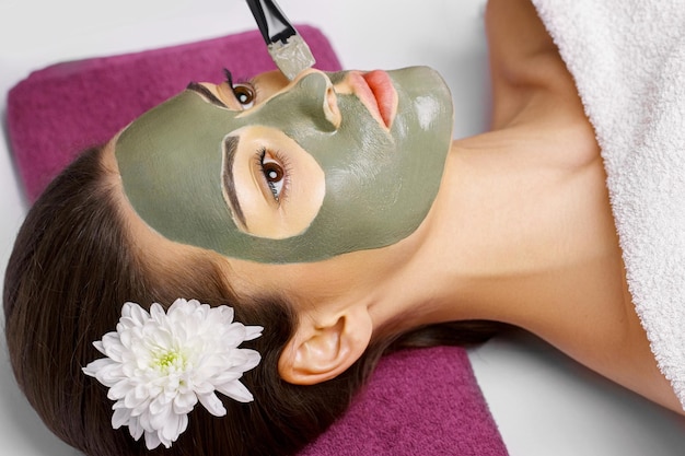 Femme avec un masque facial à l'argile dans un spa de beauté Skincare Beauty Co