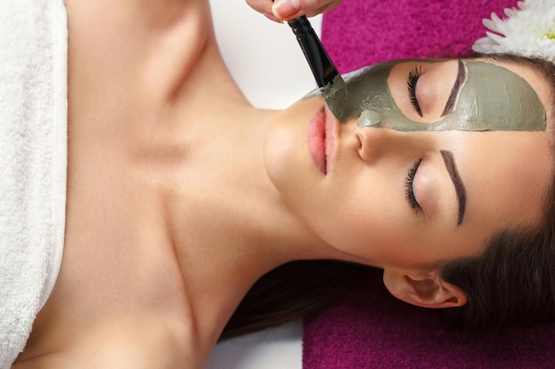 Femme avec un masque facial à l'argile dans un spa de beauté Skincare Beauty Concept Portrait en gros plan d'une belle fille