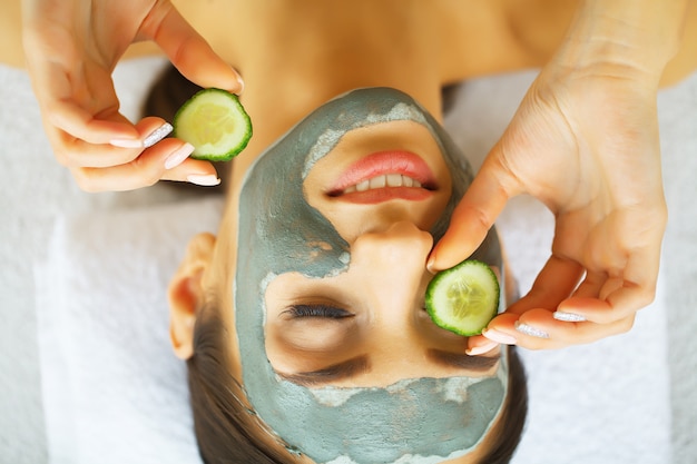 Femme, masque facial, concombre, tranches, mains