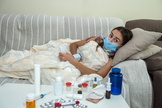 Femme avec masque facial couché dans un canapé malade de covid19.