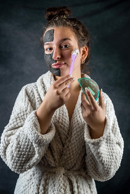 Femme avec un masque noir et blanc en argile sur la moitié du visage