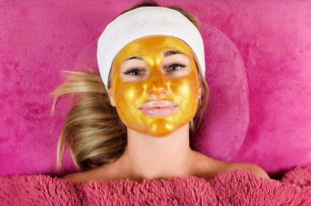 Femme avec un masque d'or au salon