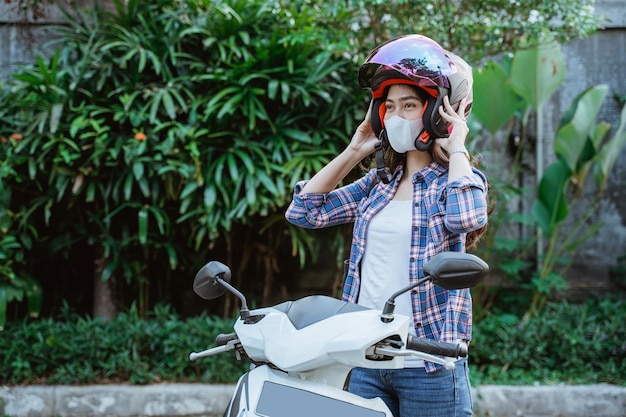 Femme avec masque portant un casque avant de conduire une moto avec fond