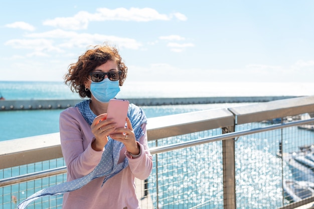 Femme avec masque de protection en regardant le téléphone