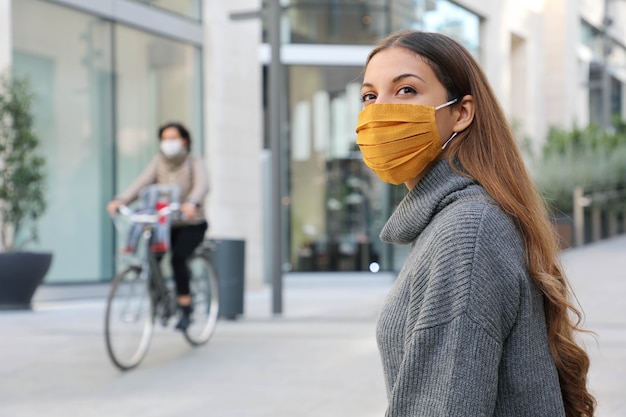 Femme avec masque de protection regarde autour de assis sur un banc en attendant des temps meilleurs dans la ville moderne