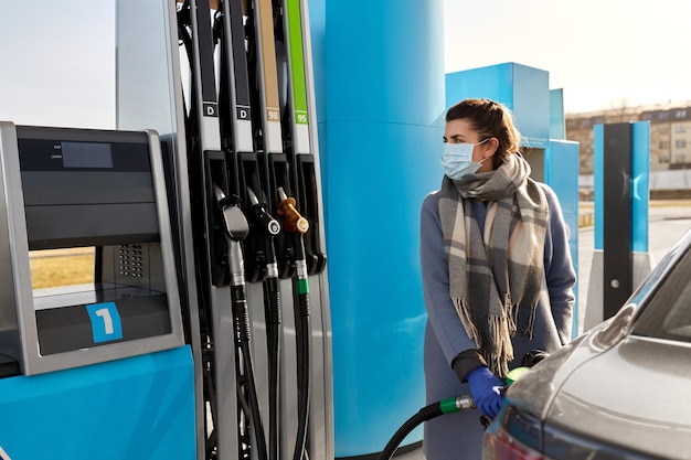 femme en masque remplissant la voiture à la station-service