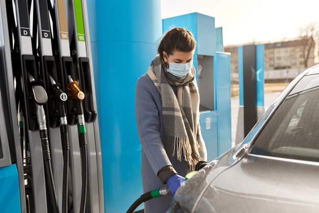 femme en masque remplissant la voiture à la station-service