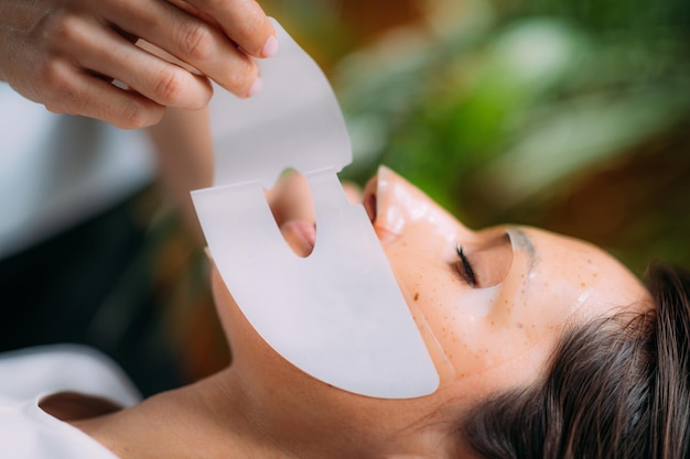 Femme avec un masque de soin de la peau dans un salon de beauté