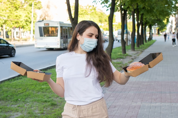 Une femme masquée tient de la nourriture de rue.