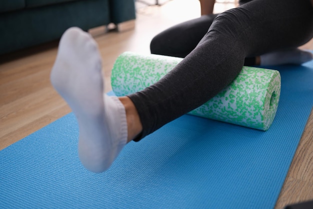 Femme massant la jambe avec un rouleau en mousse libre