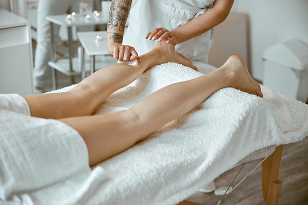 Une femme masseuse fait un massage professionnel des jambes dans un salon moderne