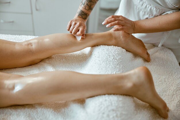 Une femme masseuse fait un massage professionnel des jambes dans un salon moderne