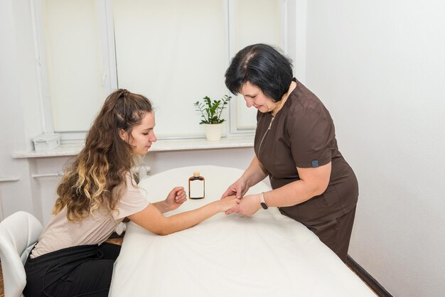 Une femme massothérapeute fait un massage des mains à une jeune fille dans un salon de massage.