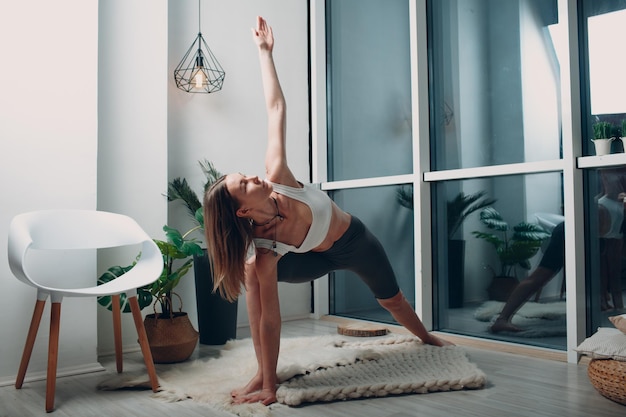 Femme mature adulte faisant du yoga dans le salon à la maison