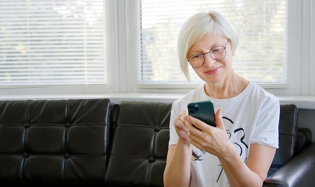 Femme mature à l'aide de téléphone. Femme d'âge moyen tenant un téléphone intelligent en regardant l'écran du téléphone portable