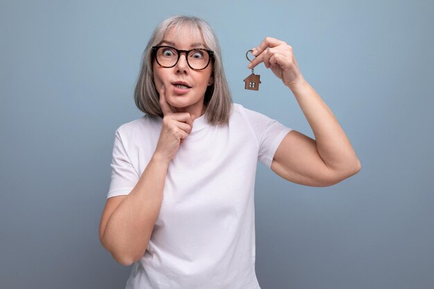 Femme mature d'assurance sociale tenant des clés sécurisées sur fond de studio