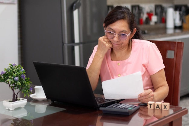 Femme mature déçue analysant les impôts et les informations financières de la maison