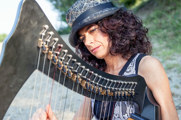 Une femme mature jouant de la harpe à l'extérieur.